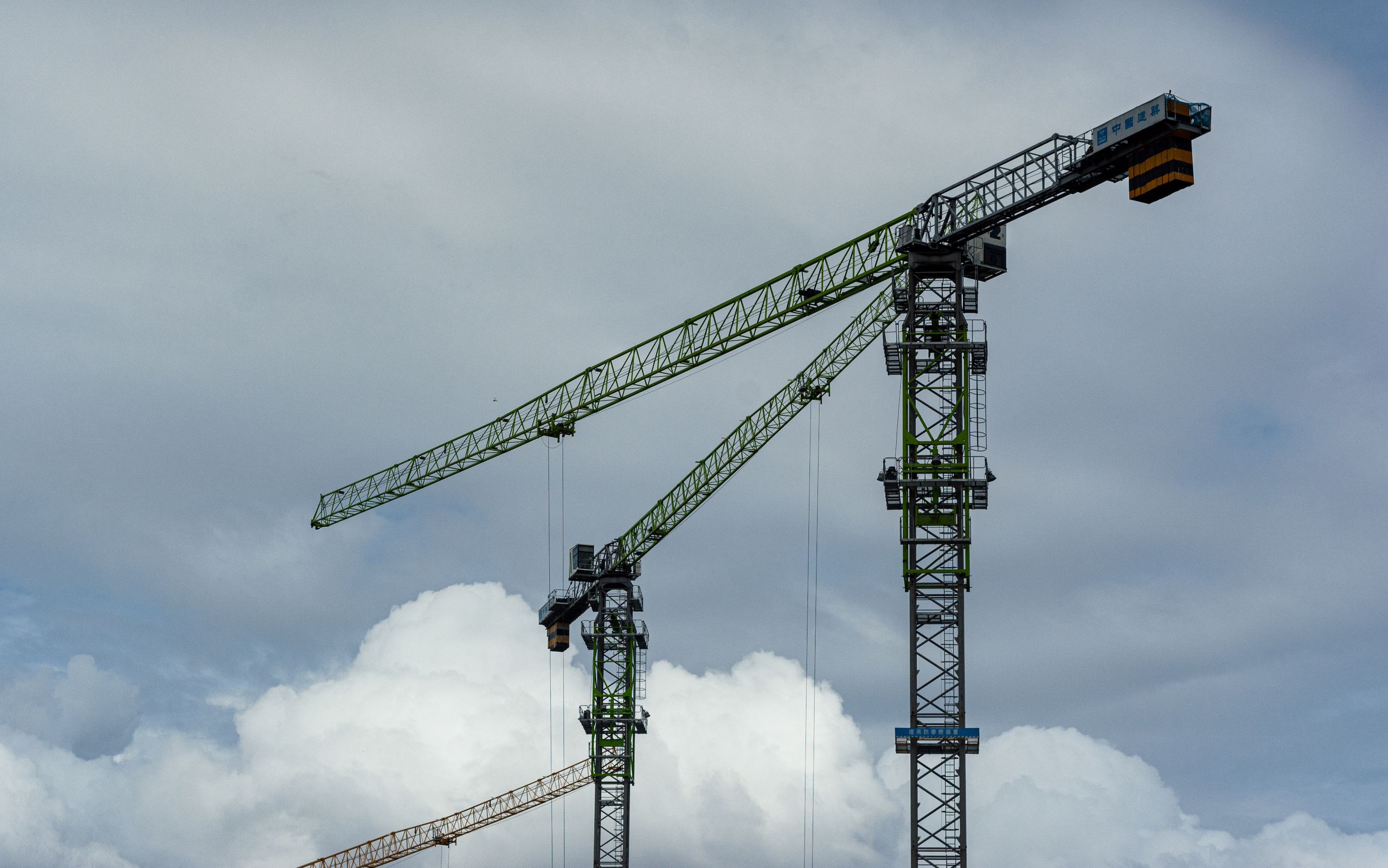 Tower Cranes Against Cloudy Blue Sky on Construction Site